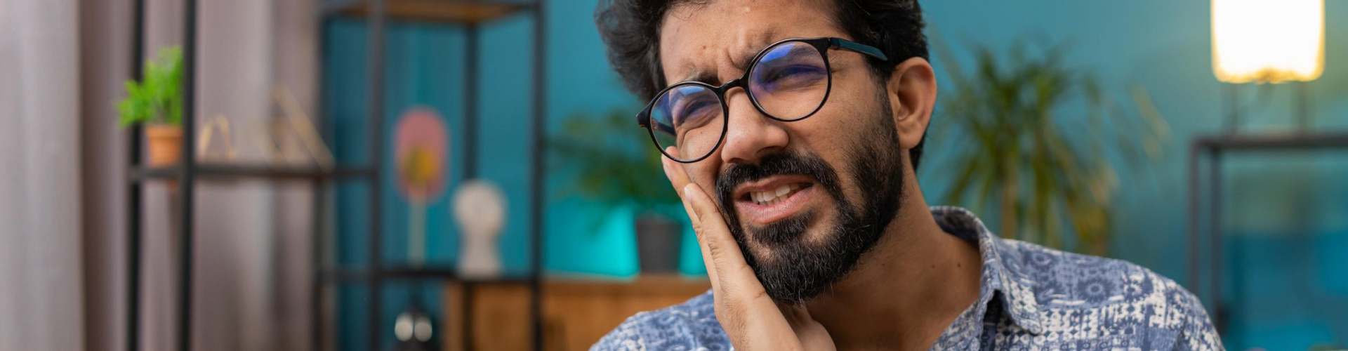 Man experiencing tooth pain while holding his cheek, suggesting a toothache or dental emergency.
